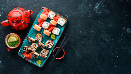 Sushi and rolls on the plate. Top view. Free space for your text. On a black background.