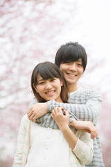 桜の前で微笑むカップル