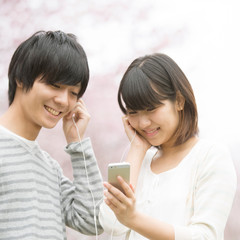 桜の前で音楽を聴くカップル