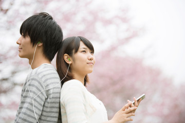 Fototapeta premium 桜の前で音楽を聴くカップル