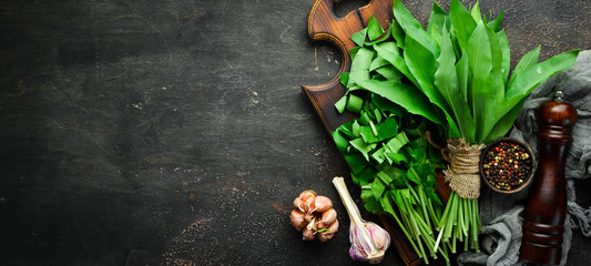 Fresh wild garlic leaves on a wooden background. Top view. Free space for your text. - obrazy, fototapety, plakaty