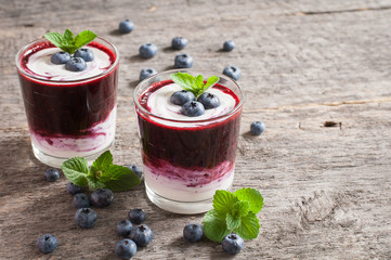 Fresh blueberry smoothies in a glass with berries and mint leaves on a wooden stand.Selective focus.