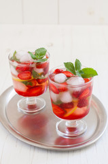 Summer cold drink . Lemonade with mint and strawberries on a light background.