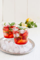 
Summer cold drink . Lemonade with mint and strawberries on a light background.