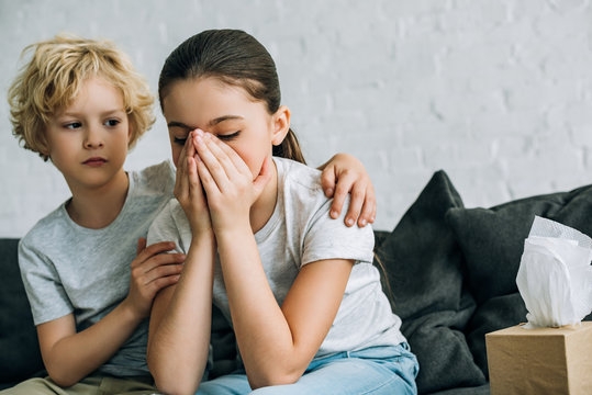 little brother consoling crying sister in living room - Powered by Adobe