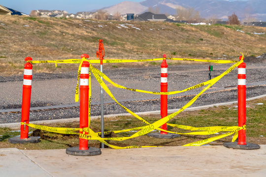 Orange traffic poles with yellow caution tape surrounding a hole on the ground