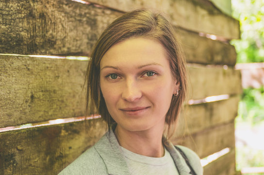 Portrait of a young attractive woman on the background of a wooden fence