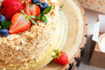 Honey cake decorated with bright strawberries and blueberries. Festive party cakes for birthday, wedding. Close-up, macro.