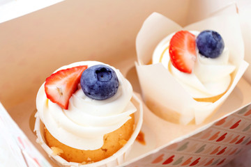 Cupcakes with whipped cream and strawberries and blueberries. Festive party cakes for birthday, wedding.