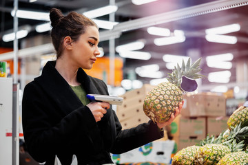Woman holding bar code scanner and scanning products in store.