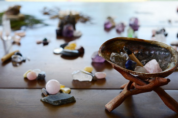 Abalone Shell with Palo Santo, and filled with healing crystals. Rose Quartz, Smokey Quartz, Sodalite, and Clear Quartz.  Burning palo santo in a abalone shell, being held. Variety of crystals shell