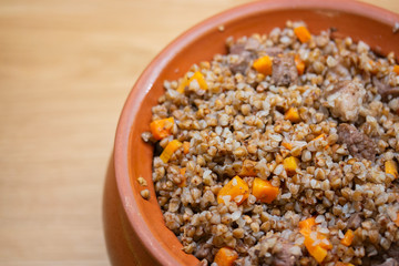 Buckwheat with meat baked in a clay pot. Buckwheat porridge with meat and vegetables cooked in pottery, close-up
