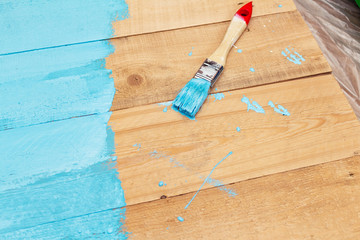 Painting with the paint brush blue color paint on the wooden DIY background for photo