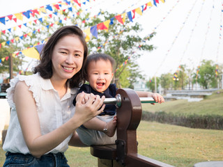 Cute Asian mother and son playing  in the park outdoors