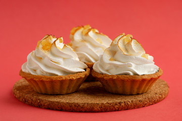 Three cream cakes on a pink background. Macro. Dessert in the form of cakes with protein cream. Cakes look like baskets. Dessert on a bright pink background.