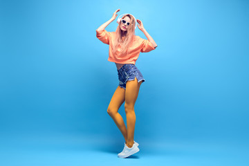 Young fashionable DJ Girl Having Fun listen to music. Beautiful slim glamor Woman dance in trendy Outfit. Adorable sexy blond hipster in Stylish neon hoodie. Lifestyle music lover concept