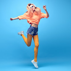 Fashion Hipster DJ Girl in trendy colorful neon Outfit jump dance. Young sexy fitness blond Woman listen to music Having Fun relax. Art neon fashionable style. Funny happy positive concept