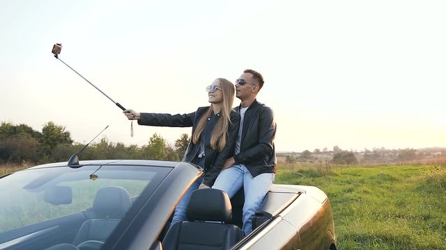 Handsome young couple taking selfie while sitting in the cabriolet.