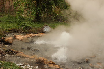 Fototapeta na wymiar steam rising and rolling from the bubbling boiling water of a volcanic hot spring in a beautiful national park near Pai, Northern Thailand, Southeast Asia
