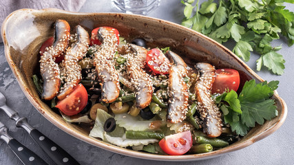 Salad with fried eel in sauce with sesame and vegetables. Top view