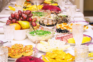 Served table. Snacks, fruits, sandwiches, salads, caviar and slicing on the holiday table. Selective focus