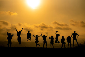 The silhouette of a group of people is celebrating success on the hilltop..