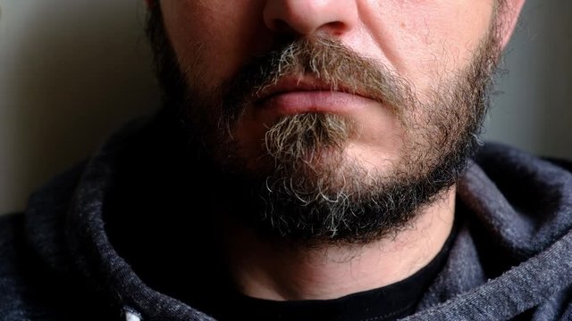 Don't speak, be quiet - close up portrait of bearded man on the door saying shh. Finger on lips. Head and shoulders, no eyes. Danger. Violence concept.