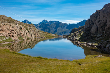 Naklejka na ściany i meble Mountain lake with reflections and grass in the Pyrenees grassMountain lake with reflections and grass in the Pyrenees, France and Spain Border