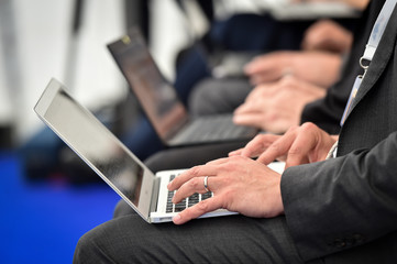 Detail with journalists hands typing on laptops during a press conference