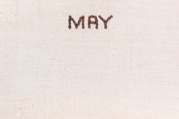The word May written with coffee beans shot from above, aligned at the top.