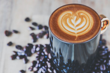close up hot latte art and coffee beans on wooden table