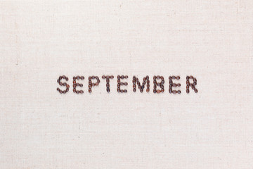 The word September written with coffee beans shot from above, aligned in the center.