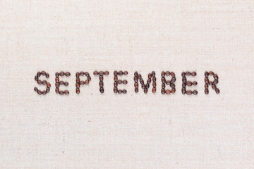 The word September written with coffee beans shot from above, aligned in the center, closeup.