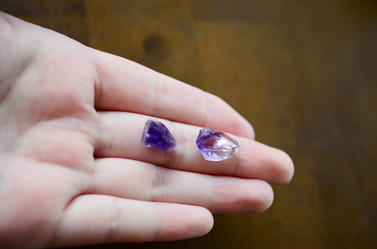 Tiny amethyst crystals being held in woman's hand, miniature crystal chips. Macro photo in natural lighting, deep purple healing crystal. Micro minerals, crisp colors. 