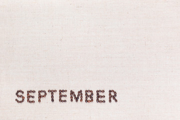 The word September written with coffee beans shot from above, aligned at the bottom left.