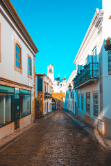 beautiful mediterranean street in a village with clock tower at the background
