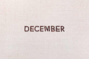 The word December written with coffee beans shot from above, aligned in the center.