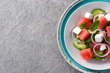 watermelon salad with feta cheese,mint,onion and cucumber on gray background.Top view. Copyspace