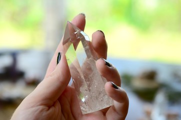 Beautiful Clear Quartz tower, and fresh pink rose flowers. Bright Quartz crystal, healing crystal being held in hand. Woman holding quartz tower, crisp colors in natural lighting. Vibrant meditation.