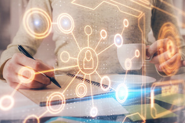 Social network theme hologram over hands taking notes background. Concept of global international people connect. Double exposure