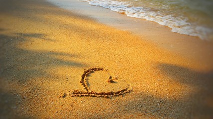  Heart shape on the sand by the sea, reflecting the morning sun