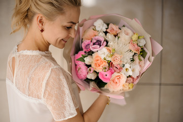 Smiling girl holding a spring bouquet of tender white and pink flowers
