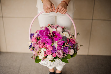 Girl holding a spring basket of tender pink, violet and white flowers