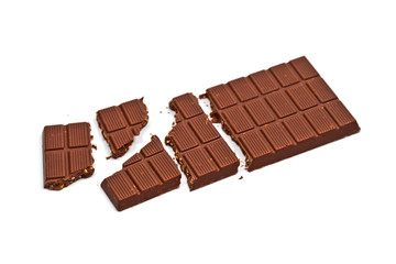 Broken milk chocolate bar with hazelnuts isolated on white.