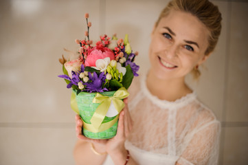 Smiling girl holding a spring green pot of tender pink, white and violet flowers