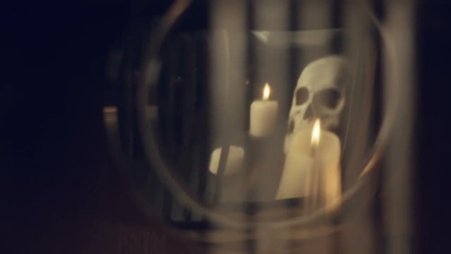 reflection of the skull and candles in the pendulum of an old clock