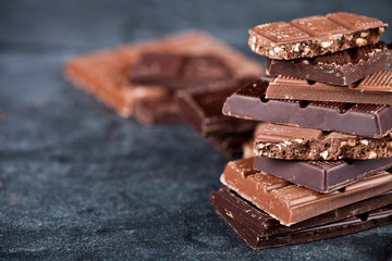 Chunks of broken chocolate stacked on black board.