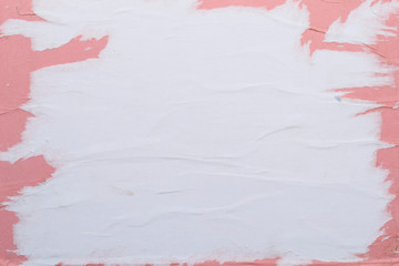 White and pink sheets of torn paper pasted on the wall.