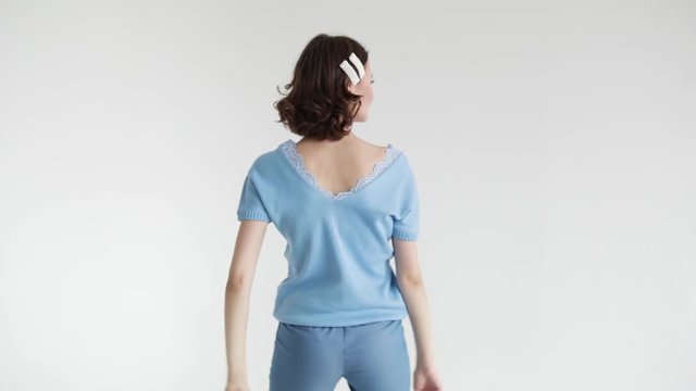 Model beautiful woman with short hair posing in the Studio on a white background in a blue jumper and blue pants. Slow mo