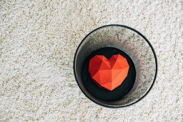 red heart in black trash can on carpet